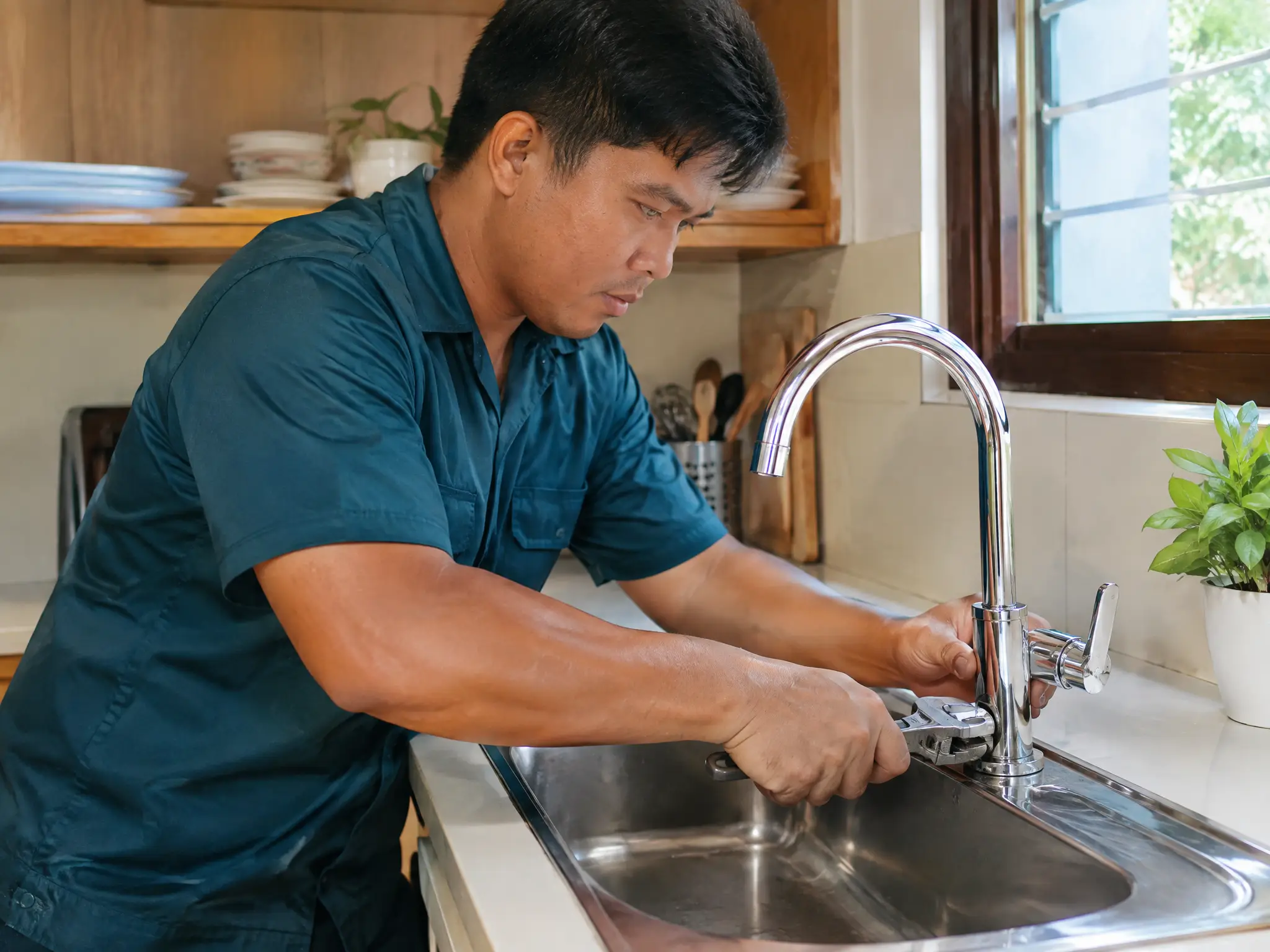 Tubero na nagkakabit ng bagong gripo sa lababo ng kusina